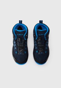 Pár tmavě modrých a černých turistických bot s jasně modrou vnitřní podšívkou a šněrováním na bílém pozadí.