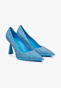 Modré vysoké podpatky vyrobené z texturované látky s špičatými špičkami a širokým jehlovým podpatkem. Vnitřek má jednolitou modrou podšívku.