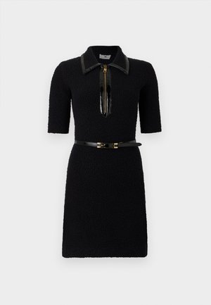 Schwarzes Kleid mit kurzen Ärmeln, strukturiertem Stoff, hohem Kragen und glänzendem Reißverschluss. Es verfügt über einen schmalen schwarzen Gürtel mit goldenen Beschlägen.