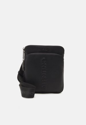 Czarna torebka crossbody Valentino z dwiema zasuwanymi przegrodami, wytłoczone logo z przodu oraz regulowanym paskiem z materiału z logo.