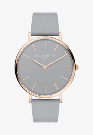 Rund ur med en grå urskive og minimalistiske roseguld time-markeringer. Har en blød grå læderrem og en slank guldfarvet bezel.