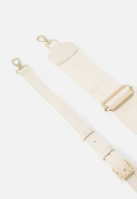 Correa ajustable de suave tela beige y cuero con herrajes dorados, que presenta dos broches y un detalle de logo en relieve en la sección más ancha.