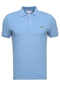 Ljusblå polotröja i texturerad tyg, med klassisk krage och två knappar, prydd med en grön krokodil-logotyp på bröstet.