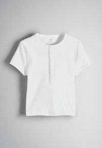 Tricou alb cu mâneci scurte, țesătură rib, cu guler rotund și o fâșie frontală cu cinci nasturi mici, afișat pe un fundal gri.