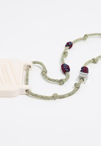 Laccio in silicone di colore rosa pallido, attaccato a un cordoncino intrecciato verde con accenti color maroon e blu, dotato di una chiusura quadrata metallica.