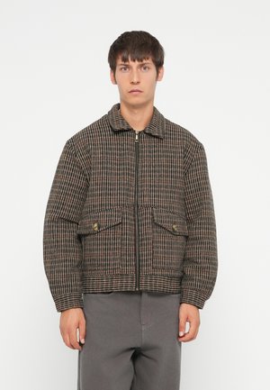 Quilted zip-up jacket in brown and black plaid with two front pockets, a collar, and ribbed cuffs. Made of a textured fabric.