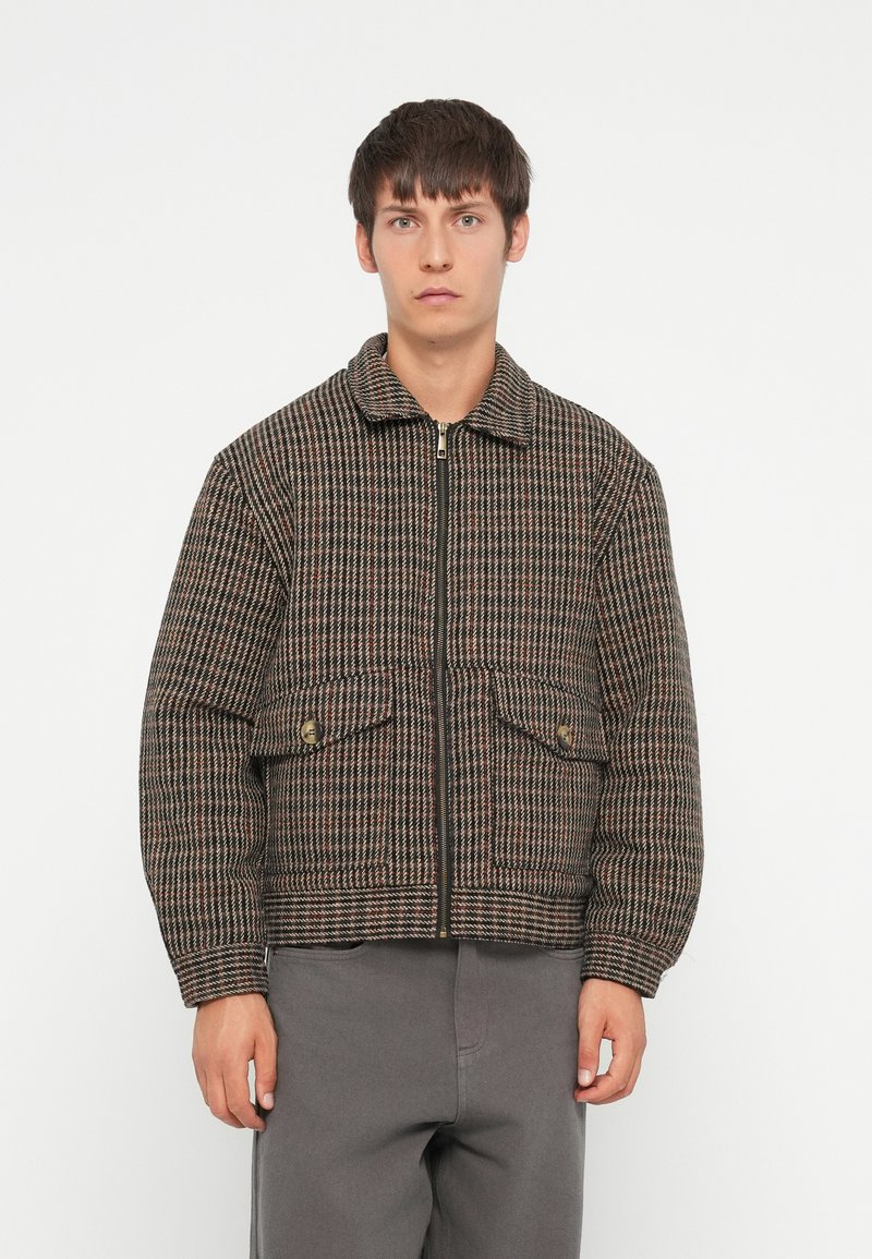 Quilted zip-jakke i brun og sort ternet mønster med to forlommer, krave og ribbede cuffs. Fremstillet af et struktureret stof.