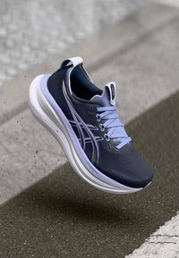 Tenniskingad, millel on tumesinine pealmine osa helesiniste detailidega, tekstureeritud pind, kerge valge tald ning iseloomulik külgmine triip.