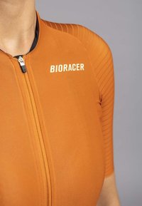 Oranje fietsjersey met een ritssluiting aan de voorkant, subtiele ribbelstructuur op de schouders en het "BIORACER" logo in het wit over de borst.