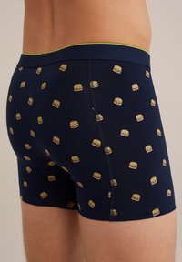 Kék boxer alsó, teljes hamburger mintával. Rugalmas anyagból készült, zöld színű derékpánttal és varrott varrásokkal.