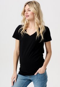 Sort v-hals T-shirt med korte ærmer, lavet af blødt stof. T-shirten har en tætsiddende pasform og bæres med blå jeans, der har et afslappet design.