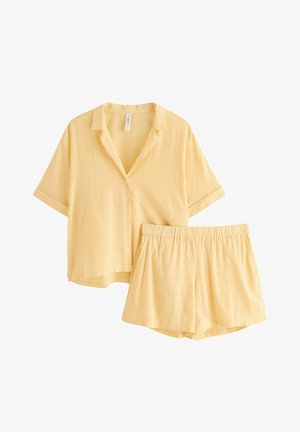 Camicia gialla chiara a maniche corte con bottoni e pantaloncini con vita elasticizzata abbinati, entrambi caratterizzati da sottili righe verticali.