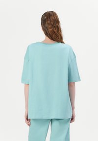 Camiseta de gran tamaño azul claro hecha de tela suave. Presenta mangas cortas, un escote redondeado y un corte relajado, con una textura suave.