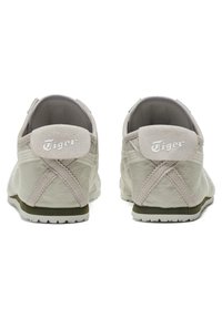 Ljusgrå sneakers med mockadetaljer, gummisulor och korsstygn. Har "Tiger"-logga på baksidan av hälen.