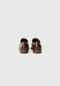 Brown leather shoes with a smooth finish, low heel, and decorative stitching. Rounded toe and minimalist design, suitable for formal wear.