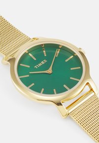 Gold-toned Timex watch with a green dial, gold hour markers, and a mesh band. The design features a round case and minimalist style.