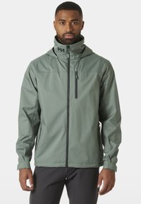 Chaqueta exterior resistente al agua en verde claro. Presenta un cuello alto, cierre de cremallera en la parte delantera, bolsillos laterales y capucha con logo. Textura suave y mate.