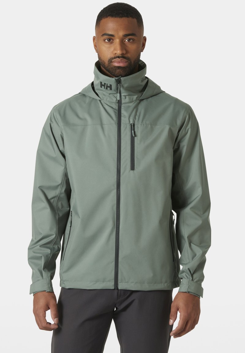 Chaqueta exterior resistente al agua en verde claro. Presenta un cuello alto, cierre de cremallera en la parte delantera, bolsillos laterales y capucha con logo. Textura suave y mate.