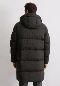 Donkergroen gewatteerd jack met capuchon, voorzien van een doorgestikt ontwerp en een oversized silhouet. Gladde, glanzende textuur, tot op de knieën reikend en met lange mouwen.