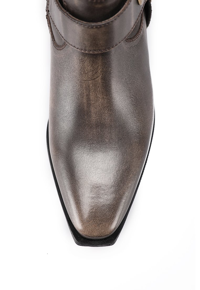 Stivale alla caviglia in pelle marrone con punta affusolata, texture liscia e hardware minimal, caratterizzato da una fascia attorno alla caviglia per un accento di design.