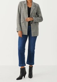 Szary marynarka w kratę o luźnym kroju, zestawiona z ciemnoniebieskimi, skróconymi dżinsami i czarnymi botkami na obcasie. Teksturowany materiał z kieszeniami.