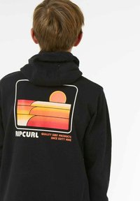 Haut à capuche noir avec un design graphique comportant des rayures dégradées orange et jaune, un soleil, et le texte "RIPCURL QUALITY SURF PRODUCTS."