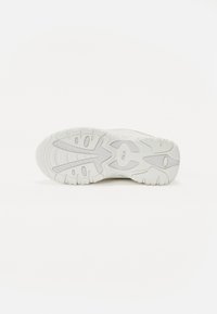 Vit sneakersula med en texturerad yta. Har distinkta greppmönster och en logotyp. Släta och något böjda kanter.