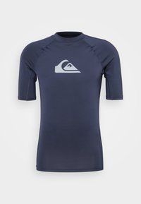 Sötétkék, rövid ujjú rash guard rugalmas anyagból. A mellrészen világosszürke logó található, és lapos varrása kényelmet biztosít.