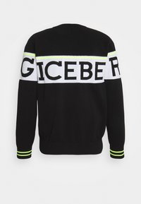 Pull noir à manches longues avec bande blanche horizontale traversant la poitrine et les bras, ornée de grandes lettres noires en gras et d'accents de bandes vert néon.