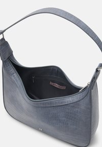 Torebka na ramię w kolorze ciemnoniebieskim, o strukturze skóry krokodyla, z szerokim paskiem, zamknięciem na zamek i wewnętrzną kieszonką. Wewnątrz widoczna metka marki "ANNA FIELD".