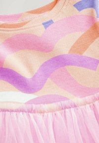 A pasztell színekben készült bordázott anyagú felső hullámos mintákkal pink, narancs és lila árnyalatokban. Világos rózsaszín tüllből készült egy rétegezett szoknya.