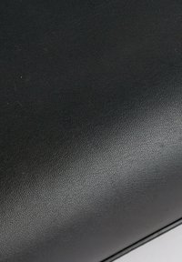 Gros plan d'une surface en cuir noir lisse avec une texture fine et un léger éclat.