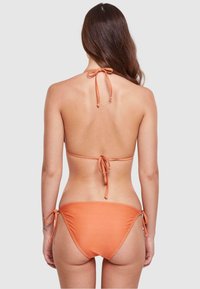 Oranje bikini met halter nekbandjes en verstelbare zijsnoeren aan de onderkant. Gladde textuur met een minimalistisch ontwerp.