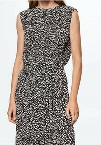 Šaty s černobílým vzorem, vysokým výstřihem, krátkými rukávy a zúženým pasem, vyrobené z lehkého materiálu s abstraktním designem.