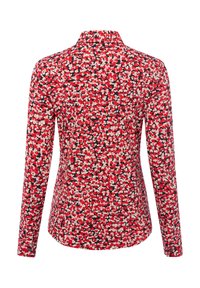 Lange mouwen shirt met een rood bloemmotief op een zwarte achtergrond, met een kraag en een afgeronde zoom. De stof lijkt glad en lichtgewicht.