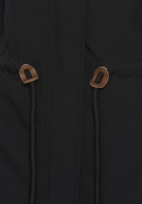 Black jacket featuring adjustable drawstrings with wooden toggles, exposed stitching, and a smooth texture.