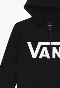 Czarna bluza z kapturem z zamkiem błyskawicznym, z dużym białym logo "VANS" z przodu, wykonana z miękkiego materiału o gładkiej teksturze. Posiada kaptur.