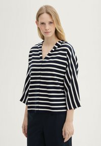 Gestreiftes Oberteil in marineblau und weiß mit V-Ausschnitt, dreiviertellangen Glockenärmeln und weicher Textur. Geeignet für die Freizeit.