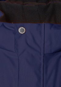 Marinblå isolerad jacka med en slät, strukturerad yta, framträdande sömmar och en märkesklädd metallknapp.