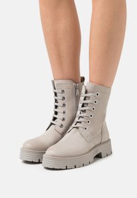 Graue Leder-Stiefeletten mit Schnürsenkeln und seitlichem Reißverschluss. Verfügt über eine robuste Gummisohle und gestickte Akzente. Glatte Textur.