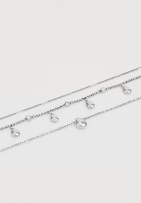 Silverfärgad lagerhalsband med delikata kedjor i varierande längder. Highlights inkluderar droppformade berlocker och små runda accenter.