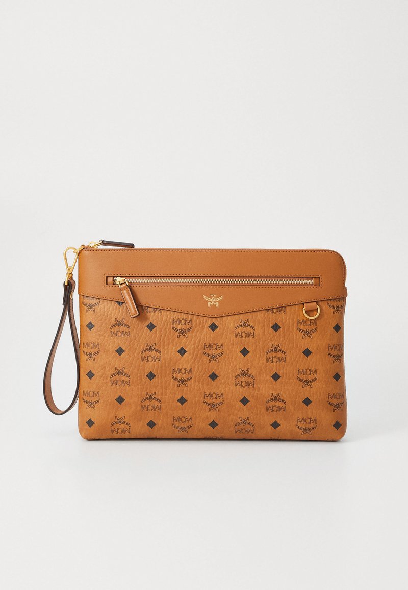 Hnědá kožená kabelka s texturovaným povrchem, s uzávěrem na zip, zápěstním popruhem a opakujícím se vzorem loga MCM v černé barvě.