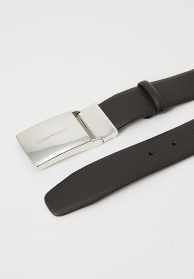 Musta tekstuuriga nahkrihm läikiva hõbedase klambriga, millel on graveeritud Emporio Armani logo valgel taustal.