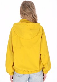 Żółta lekka kurtka przeciwdeszczowa z kapturem, elastycznym pasem i długimi rękawami, o gładkiej teksturze i minimalistycznym designie.