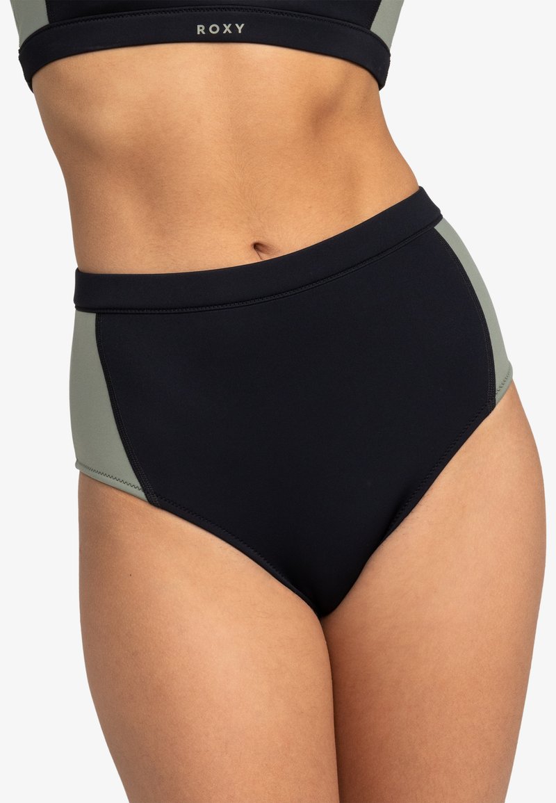Hochgeschnittene Badehosen mit einem Farbschema in Schwarz und Olivgrün. Hergestellt aus glattem, elastischem Stoff mit verstärkten Nähten.