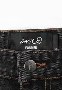 Black denim fabric with orange stitching, featuring a metal button closure and a black label displaying "DAVE FORMER" and size 33.