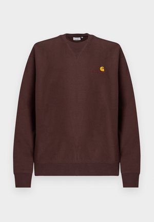 Smeđa majica dugih rukava od pamuka s okruglim izrezom, rebrastim manžetama i malim žutim logom na prsima. Glatka tekstura, opušteni kroj.