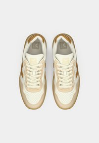 Sneakers con parte superiore in pelle bianca e beige, dettagli traforati, lacci e suola in gomma beige. Marchio sulla lingua e sul lato.