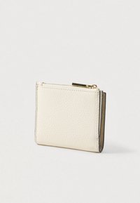 Μικρό λευκό δερμάτινο πορτοφόλι με υφή pebble και χρυσό φερμουάρ στην κορυφή, τοποθετημένο σε ένα απλό ανοιχτό φόντο.