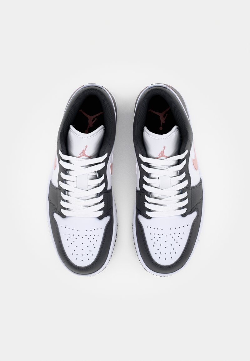 Zapatillas deportivas de corte bajo en negro y blanco con acentos en rosa, que cuentan con una caja de dedos perforada, cordones planos y un logo en la lengüeta.